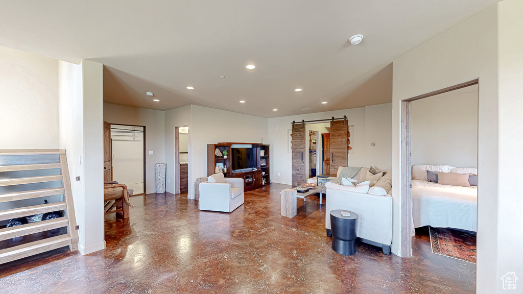 Living area with a barn door, recessed lighting, and finished concrete flooring