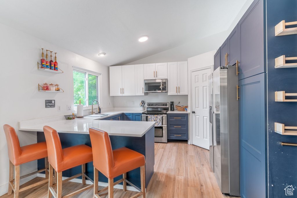 Kitchen with stainless steel appliances, a sink, lofted ceiling, a peninsula, and a breakfast bar area