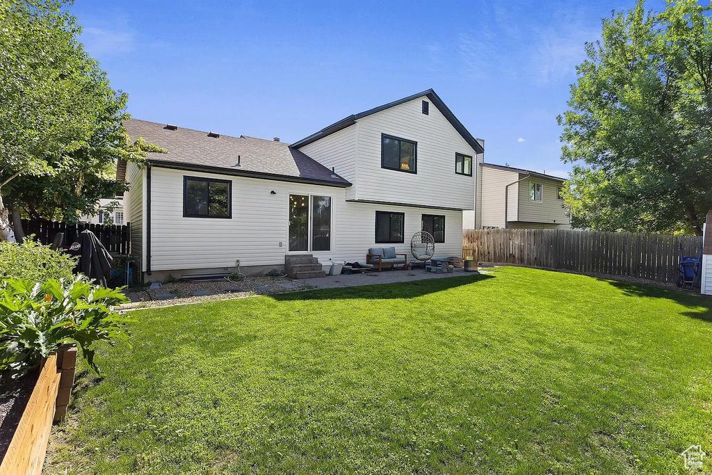 Rear view of property with entry steps, a patio, and a shingled roof