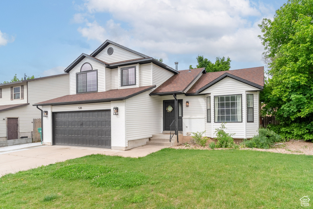 View of front of property with a garage, driveway, and roof with shingles