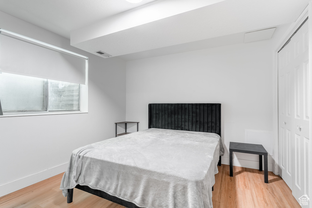 Bedroom featuring light wood finished floors, a closet, baseboards, and attic access