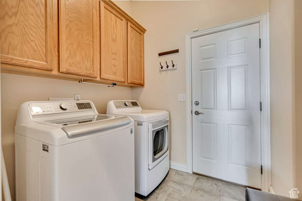 Washroom with separate washer and dryer, cabinet space, and light marble finish flooring
