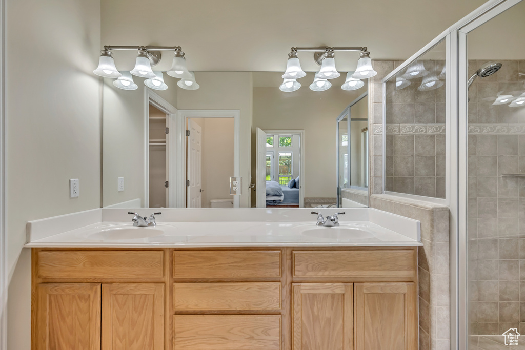 Ensuite bathroom featuring a stall shower, double vanity, and toilet