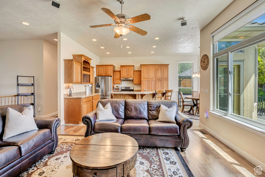 Living area with light wood-type flooring, baseboards, a ceiling fan, and recessed lighting