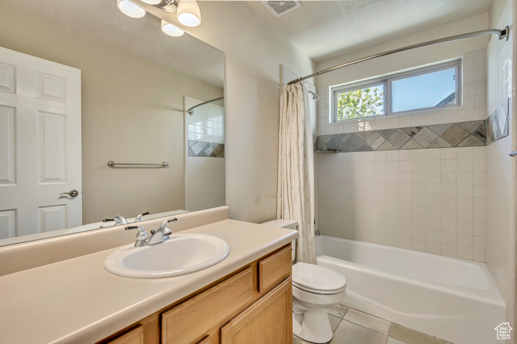Full bathroom featuring vanity, shower / bath combo, tile patterned floors, and toilet