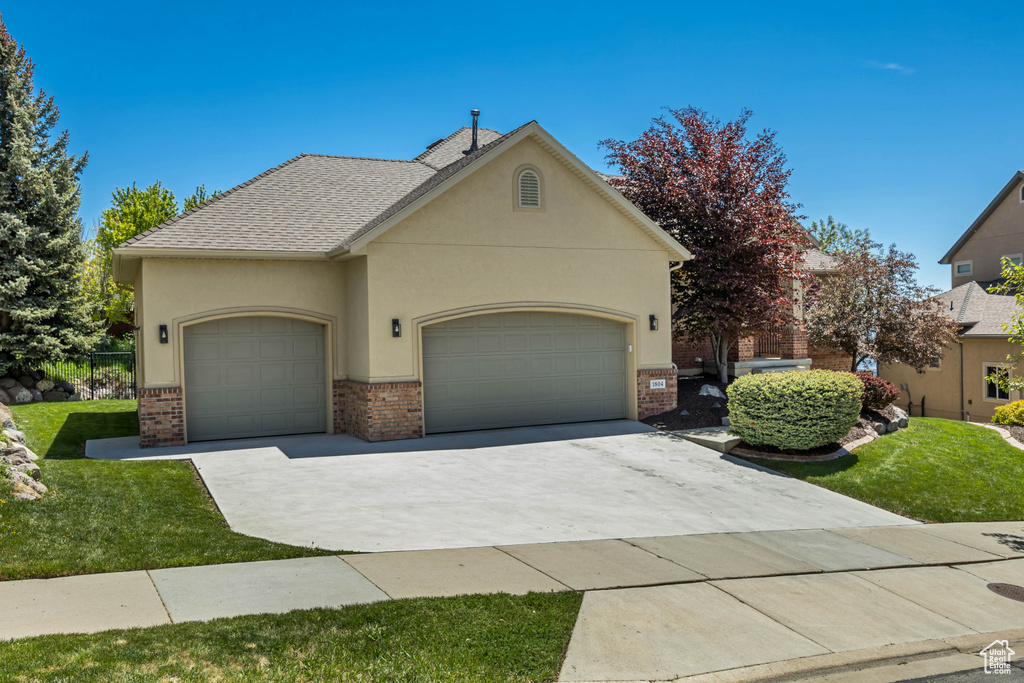 View of front facade with brick siding, a garage, and concrete driveway