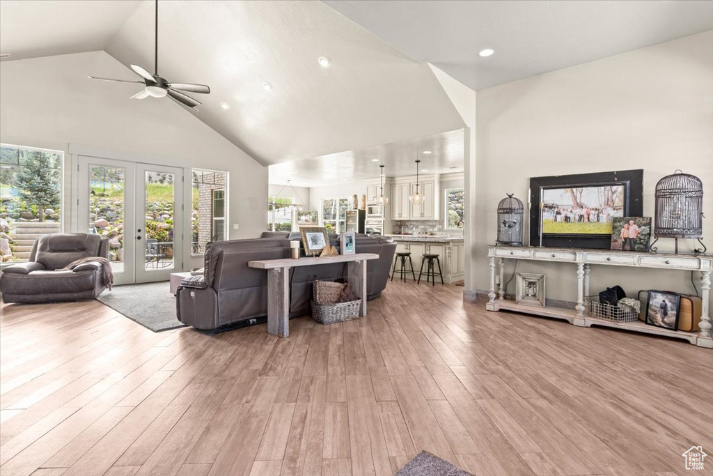 Living room featuring a ceiling fan, high vaulted ceiling, plenty of natural light, light wood-type flooring, and recessed lighting