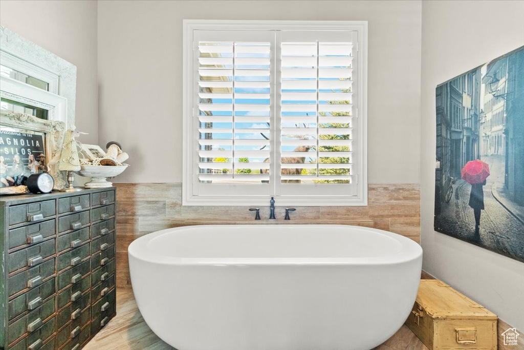 Bathroom with a soaking tub, tile walls, and wainscoting