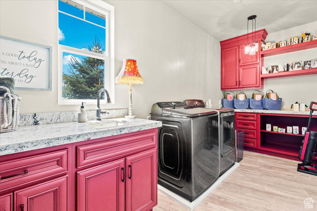 Washroom featuring washer and dryer, light wood-style floors, and cabinet space