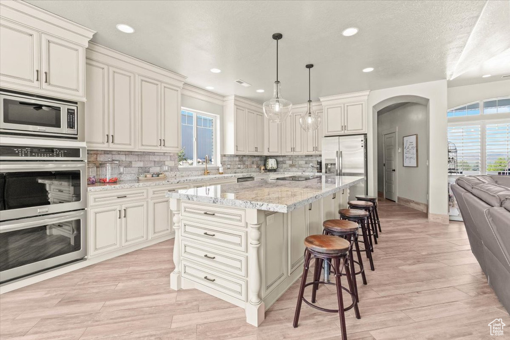 Kitchen featuring stainless steel appliances, arched walkways, healthy amount of natural light, a sink, and recessed lighting