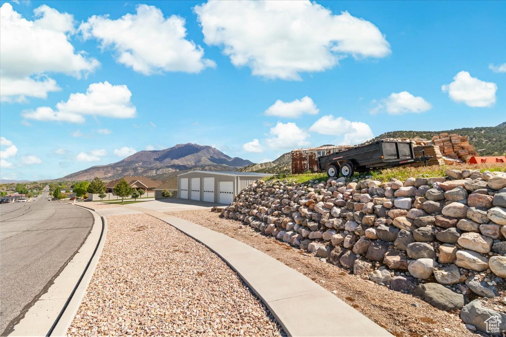 View of property's community featuring concrete driveway, a mountain view, a garage, and an outbuilding