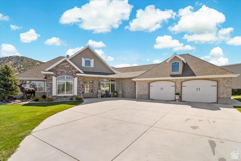 View of front facade featuring a front yard, concrete driveway, brick siding, an attached garage, and roof with shingles