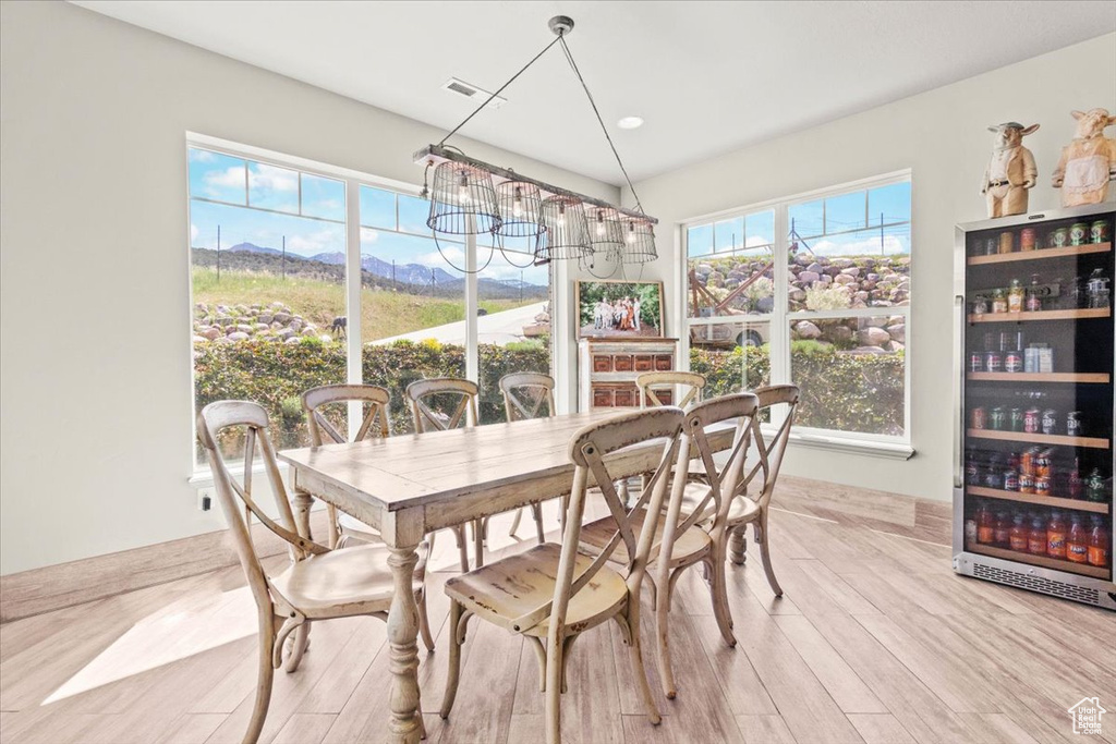 Dining area featuring beverage cooler, light wood-style flooring, a chandelier, and a mountain view
