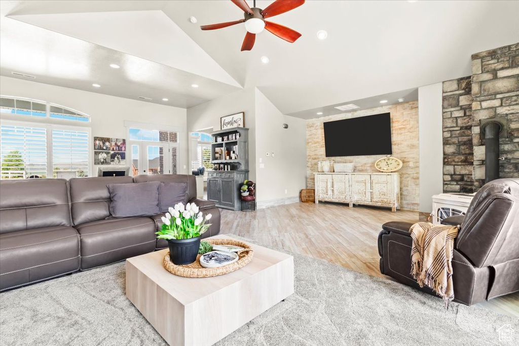 Living area with ceiling fan, wood finished floors, recessed lighting, a wood stove, and high vaulted ceiling