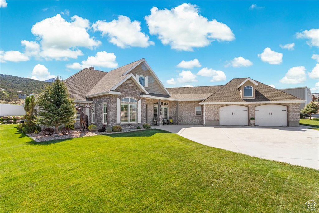 View of front of property with concrete driveway, a garage, a front lawn, and a shingled roof