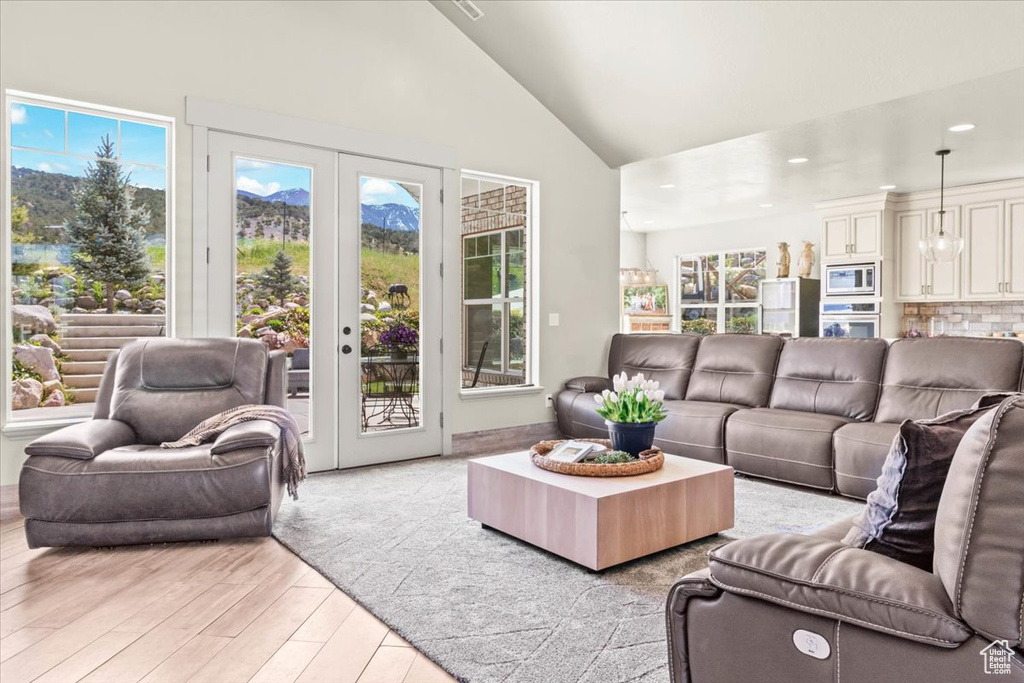 Living room with light wood-type flooring, recessed lighting, french doors, and high vaulted ceiling