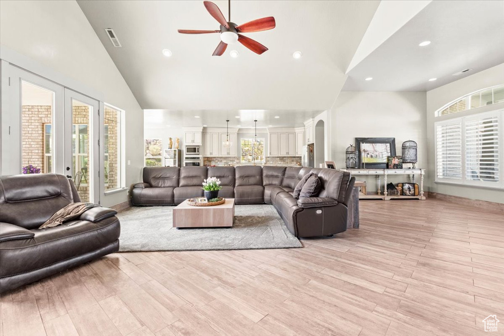 Living room with high vaulted ceiling, a ceiling fan, healthy amount of natural light, light wood-type flooring, and recessed lighting