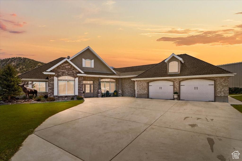 View of front of house with a lawn, concrete driveway, brick siding, a garage, and roof with shingles