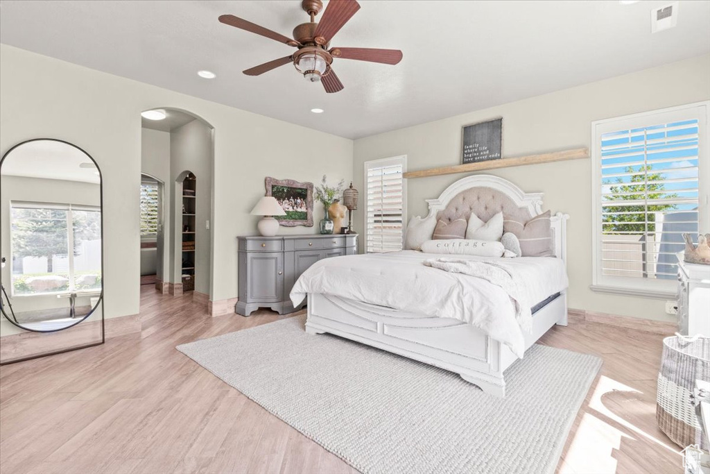 Bedroom with arched walkways, light wood-type flooring, recessed lighting, baseboards, and ceiling fan