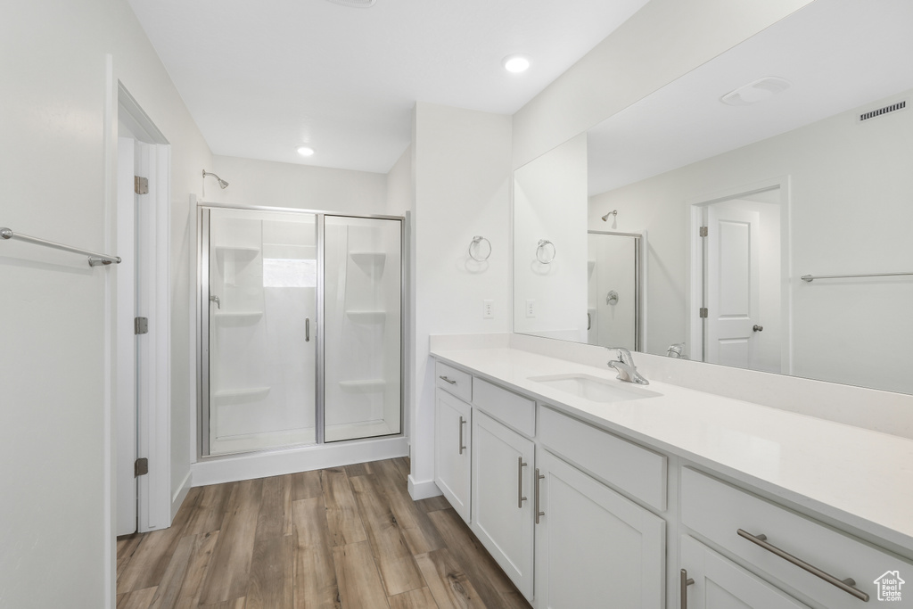 Full bathroom with a stall shower, vanity, wood finished floors, and recessed lighting