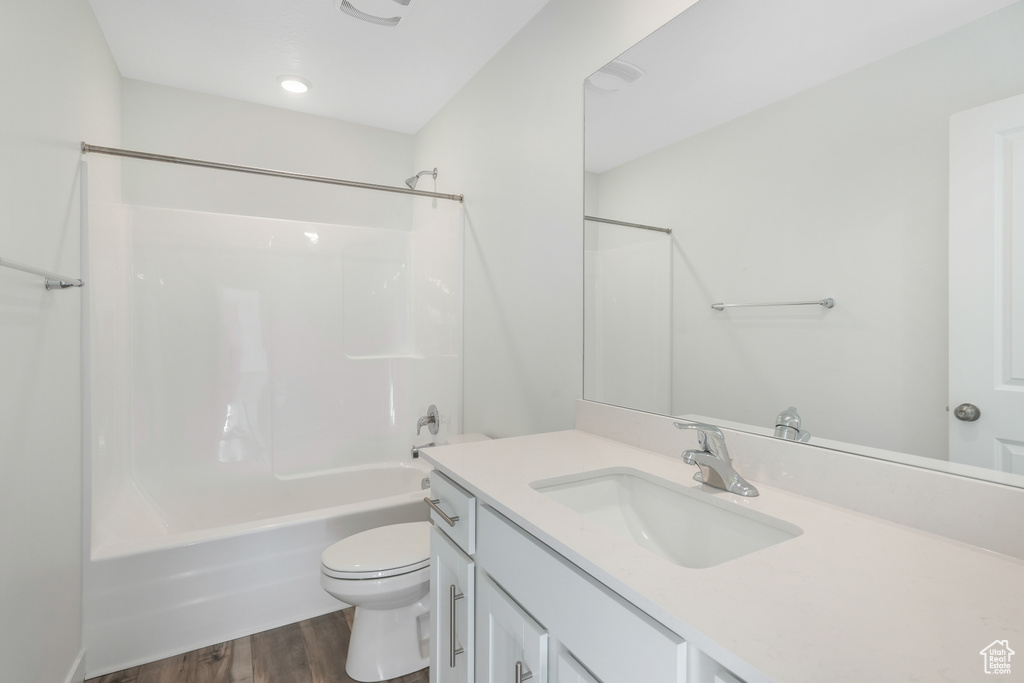Full bath featuring toilet, vanity, wood finished floors, and bathtub / shower combination