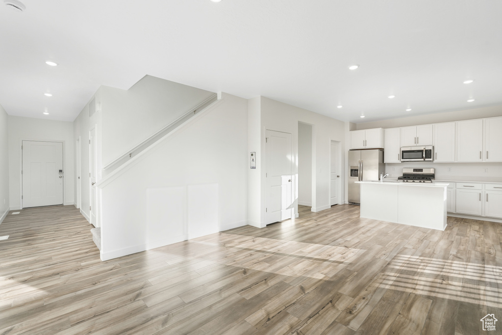 Kitchen featuring stainless steel appliances, open floor plan, light wood finished floors, and recessed lighting