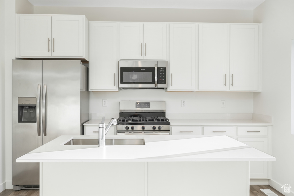 Kitchen with stainless steel appliances, a sink, light wood-style flooring, and white cabinetry
