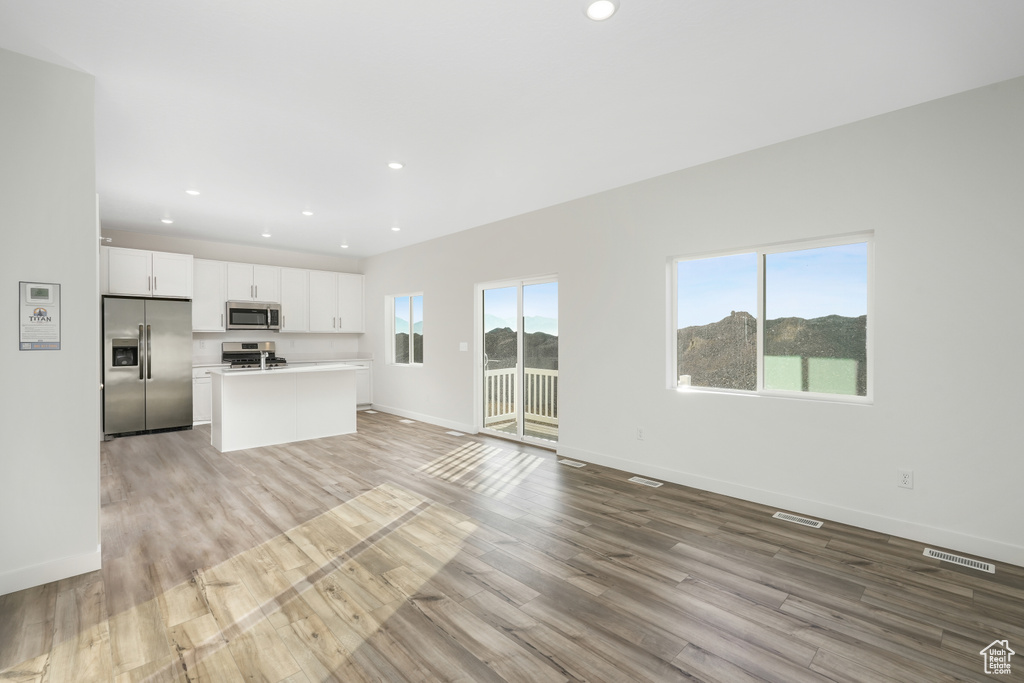 Unfurnished living room with light wood-type flooring, baseboards, and recessed lighting