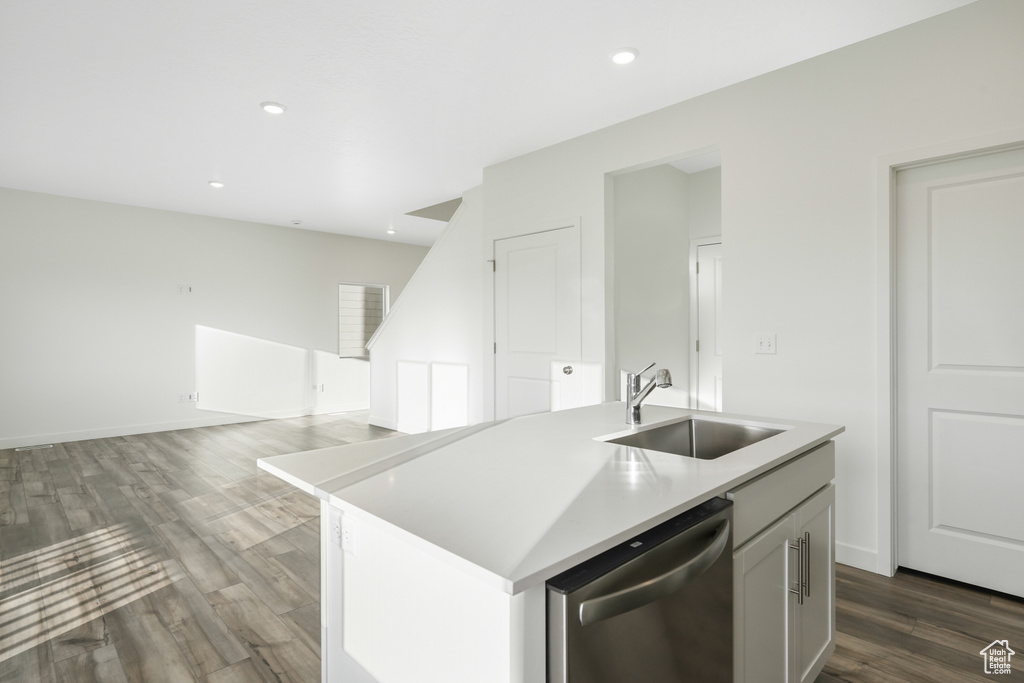 Kitchen with stainless steel dishwasher, a sink, dark wood-style flooring, light countertops, and recessed lighting