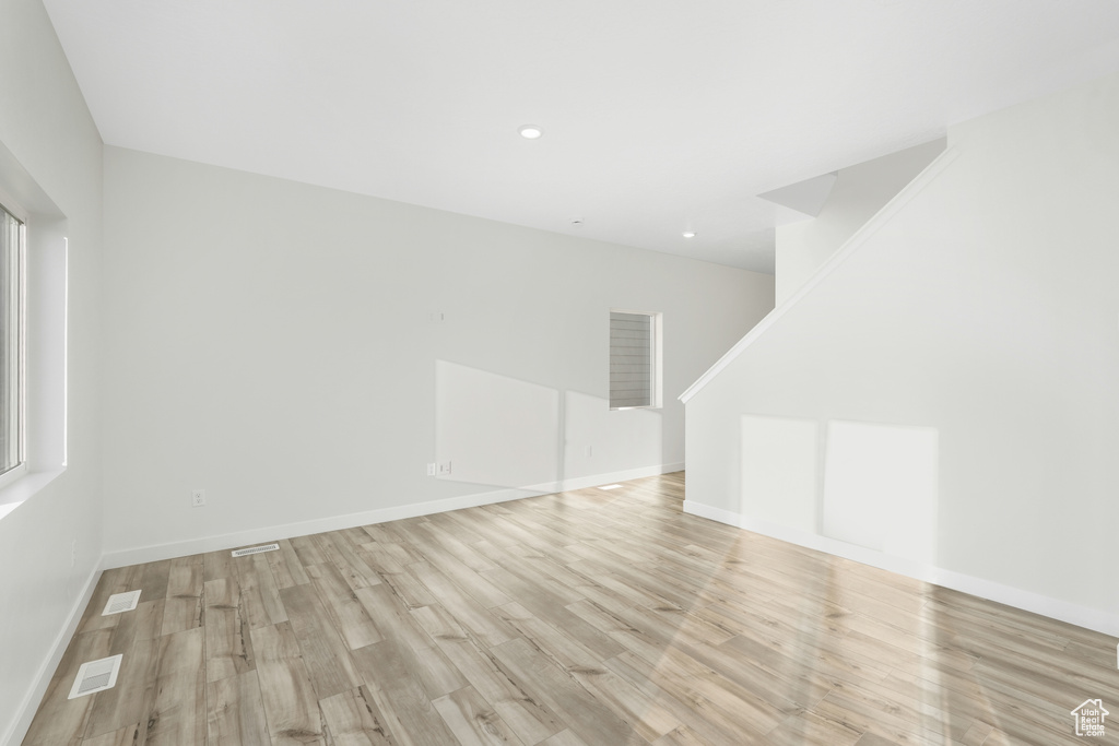 Unfurnished living room featuring light wood-style flooring, baseboards, recessed lighting, and stairs