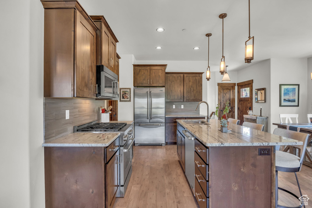 Kitchen featuring appliances with stainless steel finishes, a kitchen breakfast bar, a sink, recessed lighting, and tasteful backsplash