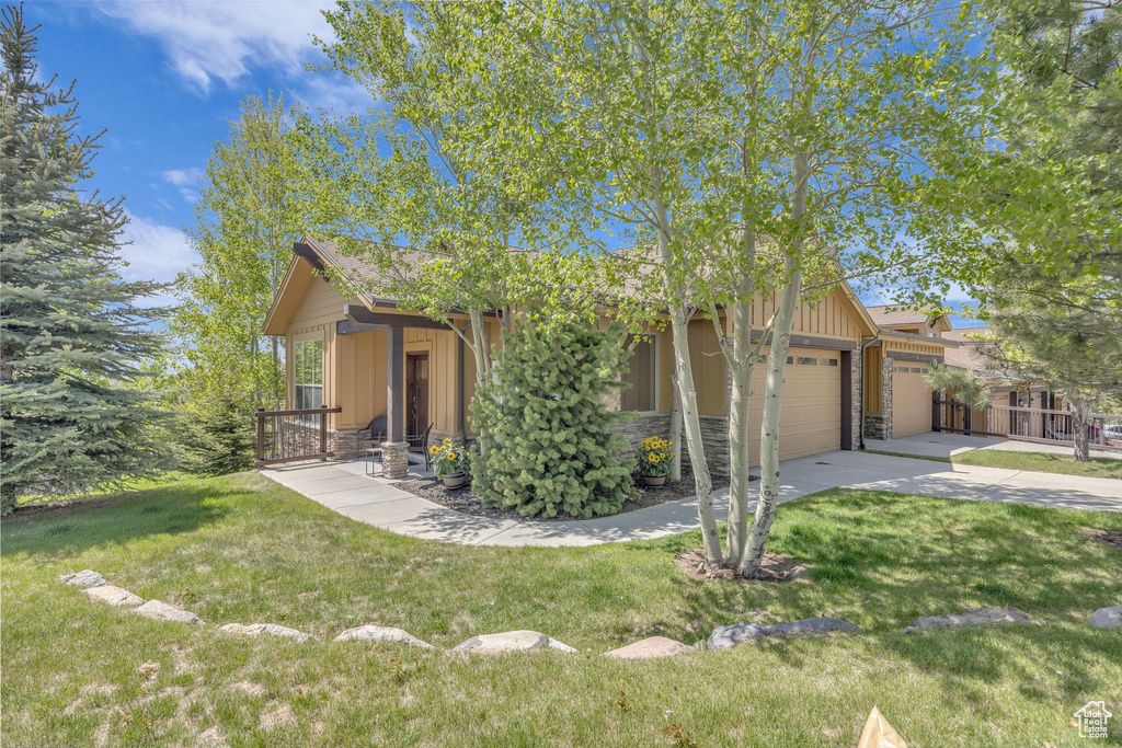 View of front of house featuring an attached garage, stone siding, board and batten siding, and driveway