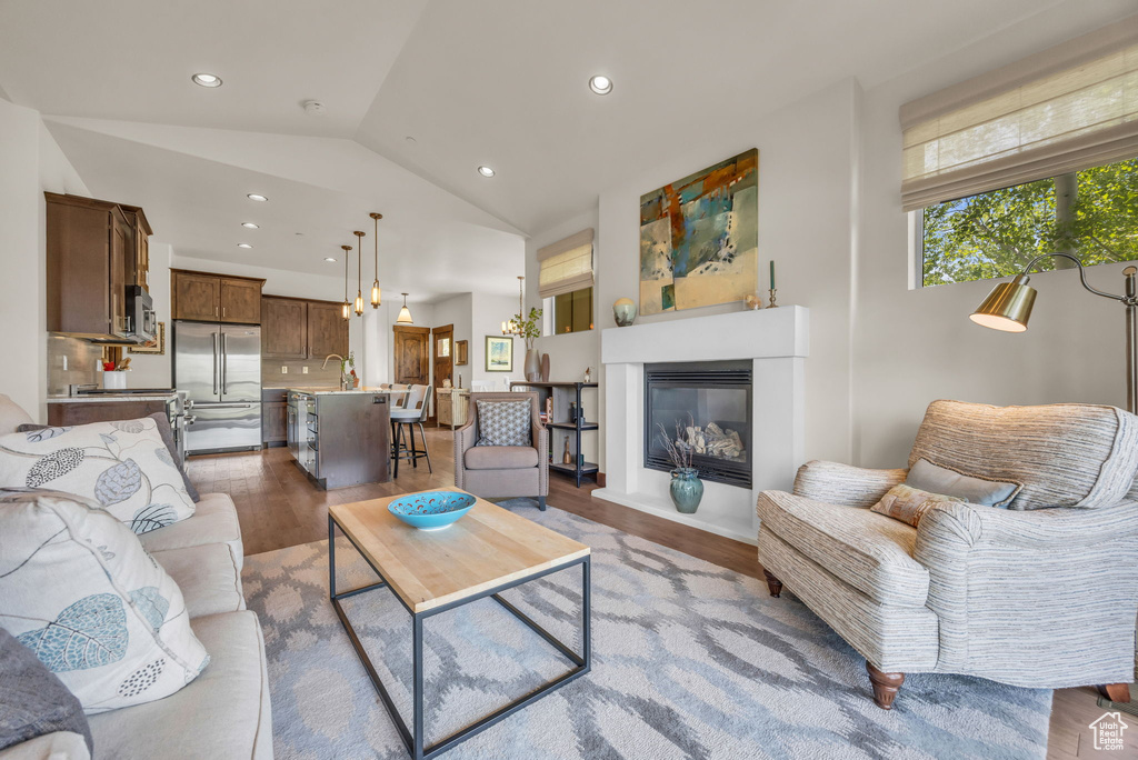 Living area featuring lofted ceiling, wood finished floors, recessed lighting, and a glass covered fireplace