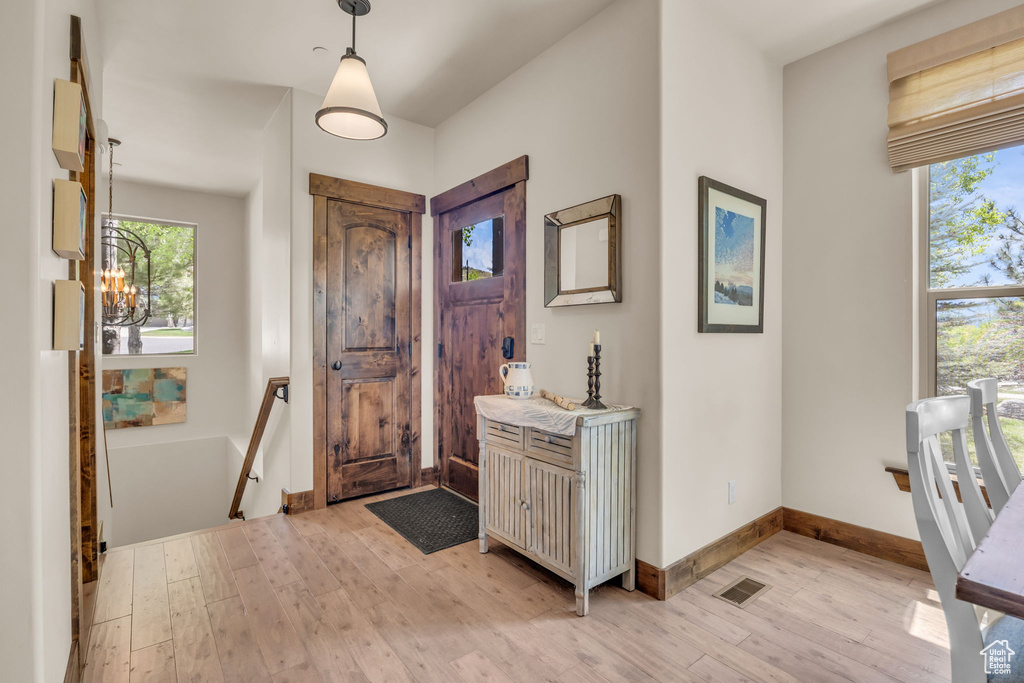 Entrance foyer with light wood-style flooring, a chandelier, and baseboards