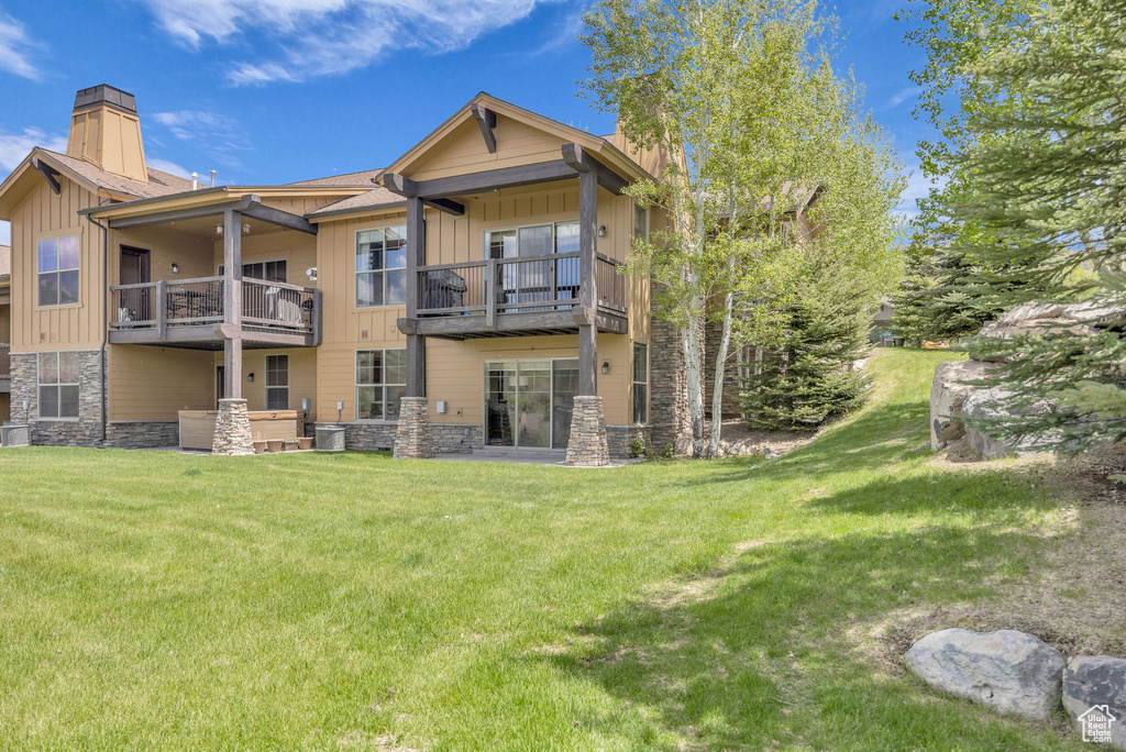 Back of property featuring stone siding, a balcony, and board and batten siding