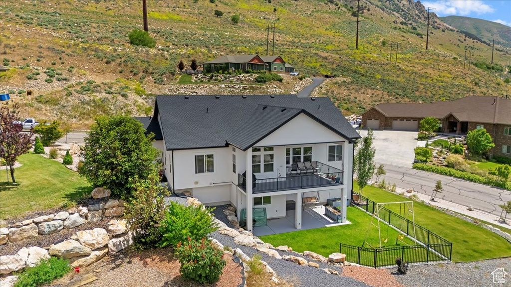 Back of house featuring a patio area, stucco siding, roof with shingles, a mountain view, and a gate