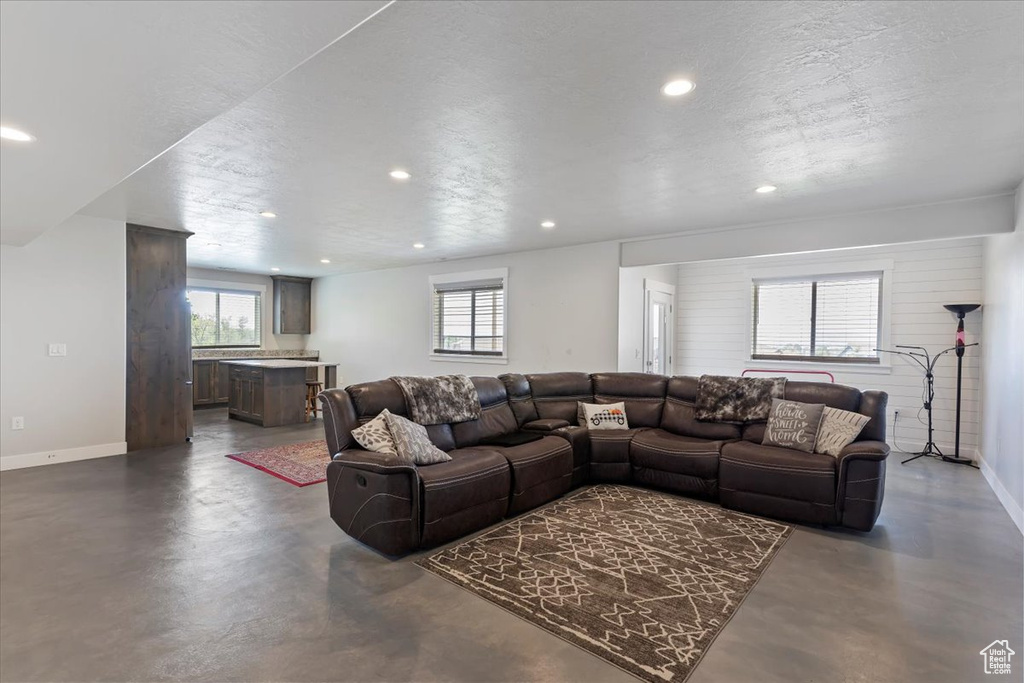 Living area with finished concrete floors, recessed lighting, baseboards, healthy amount of natural light, and a textured ceiling