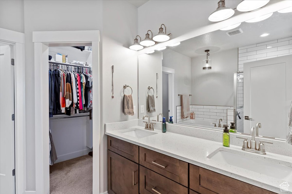 Bathroom with double vanity, a garden tub, and a spacious closet