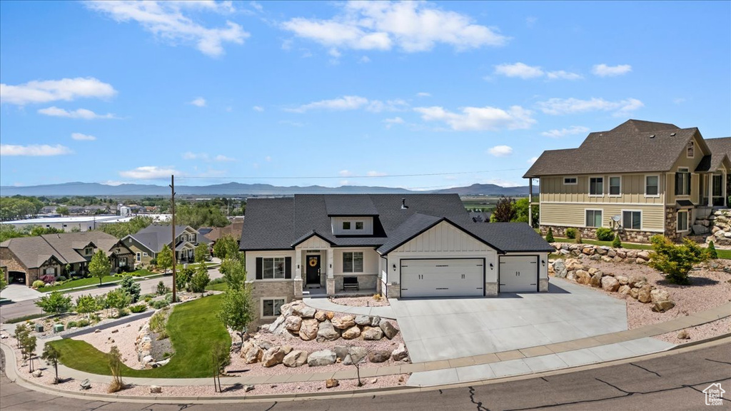View of front facade with a mountain view, a garage, board and batten siding, and concrete driveway