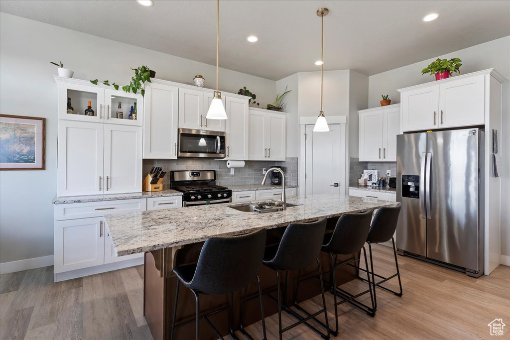 Kitchen with stainless steel appliances, a sink, backsplash, a kitchen island with sink, and recessed lighting