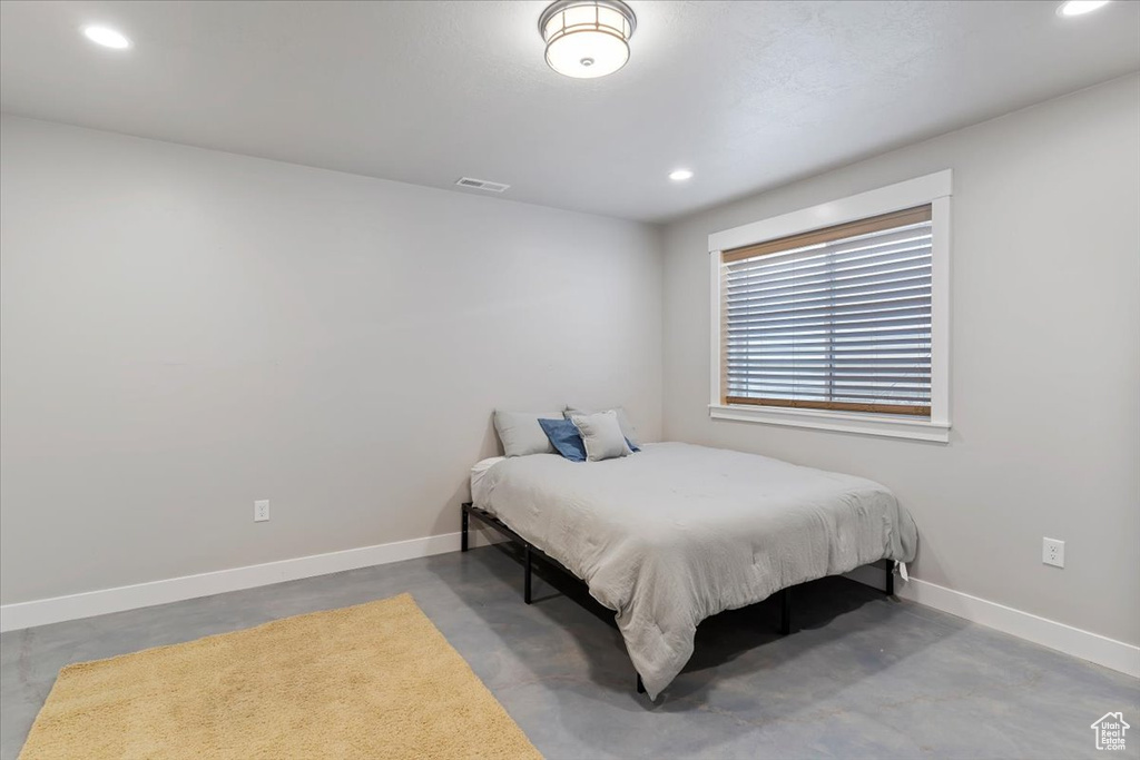 Bedroom with concrete flooring, recessed lighting, and baseboards