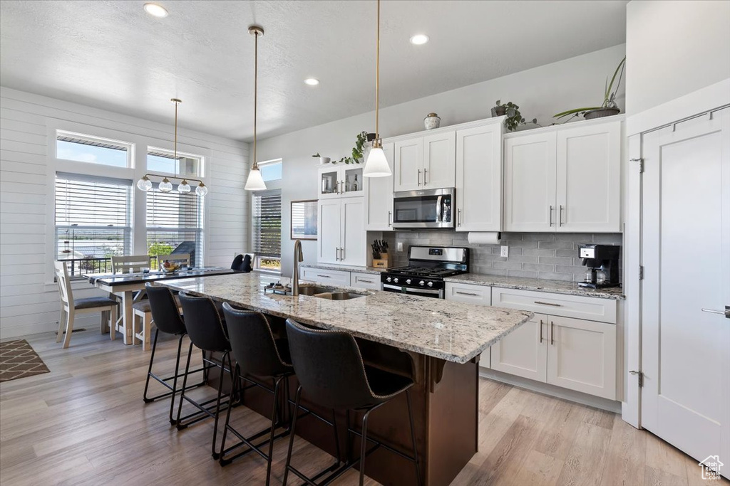 Kitchen with stainless steel appliances, a sink, decorative backsplash, recessed lighting, and a breakfast bar area