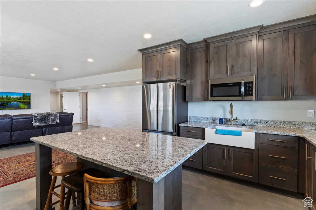 Kitchen featuring appliances with stainless steel finishes, a sink, concrete floors, dark brown cabinetry, and recessed lighting
