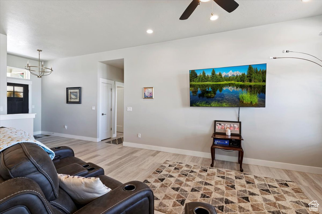 Living room with light wood-style floors, a chandelier, ceiling fan, baseboards, and recessed lighting