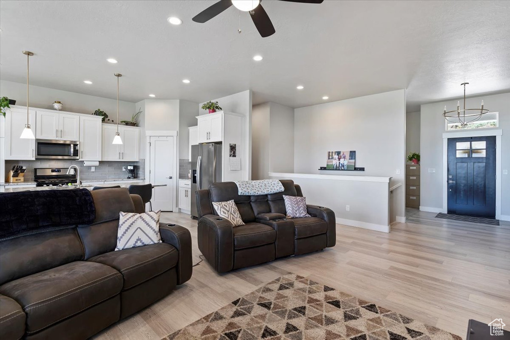 Living area with light wood-style floors, ceiling fan, baseboards, recessed lighting, and a chandelier