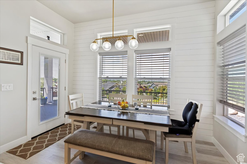 Dining area with wood finished floors, plenty of natural light, baseboards, and wood walls