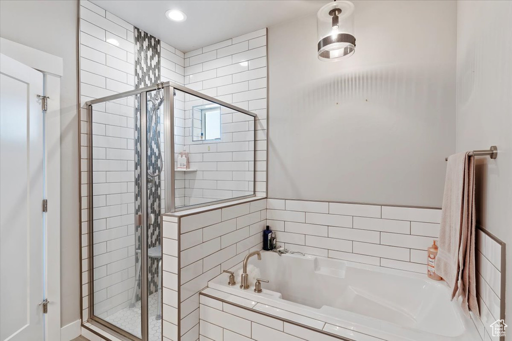 Bathroom with a shower stall, a bath, and recessed lighting