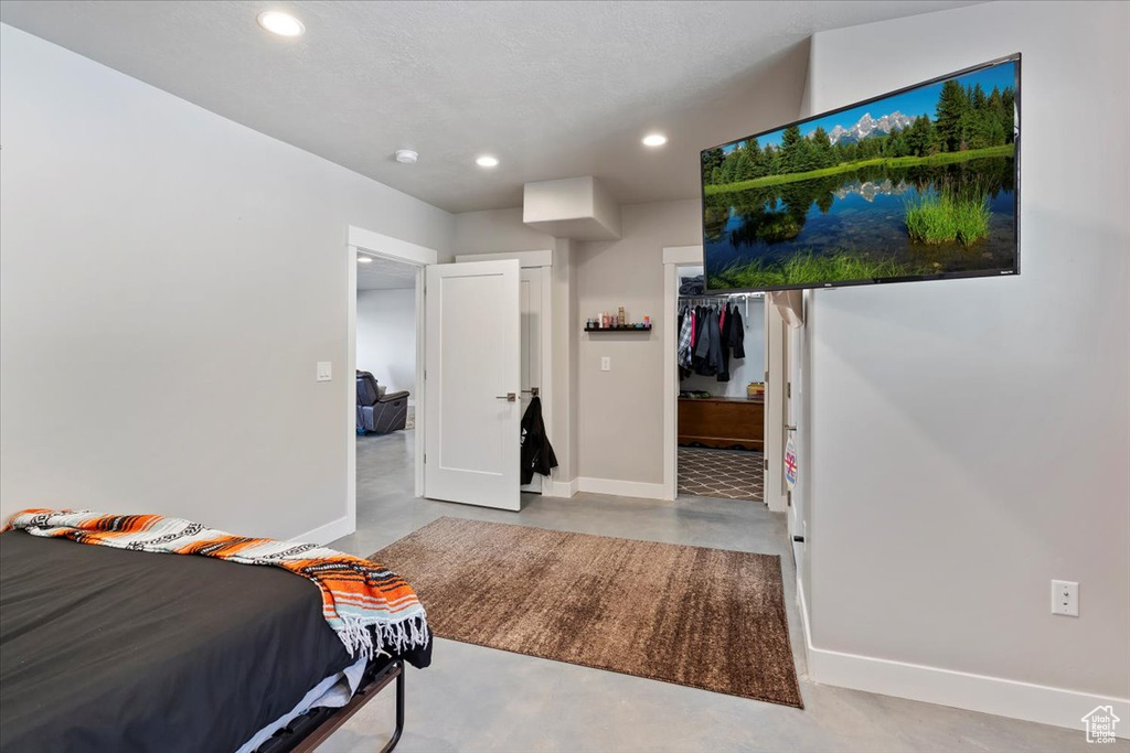 Bedroom featuring concrete flooring, recessed lighting, baseboards, a walk in closet, and a closet
