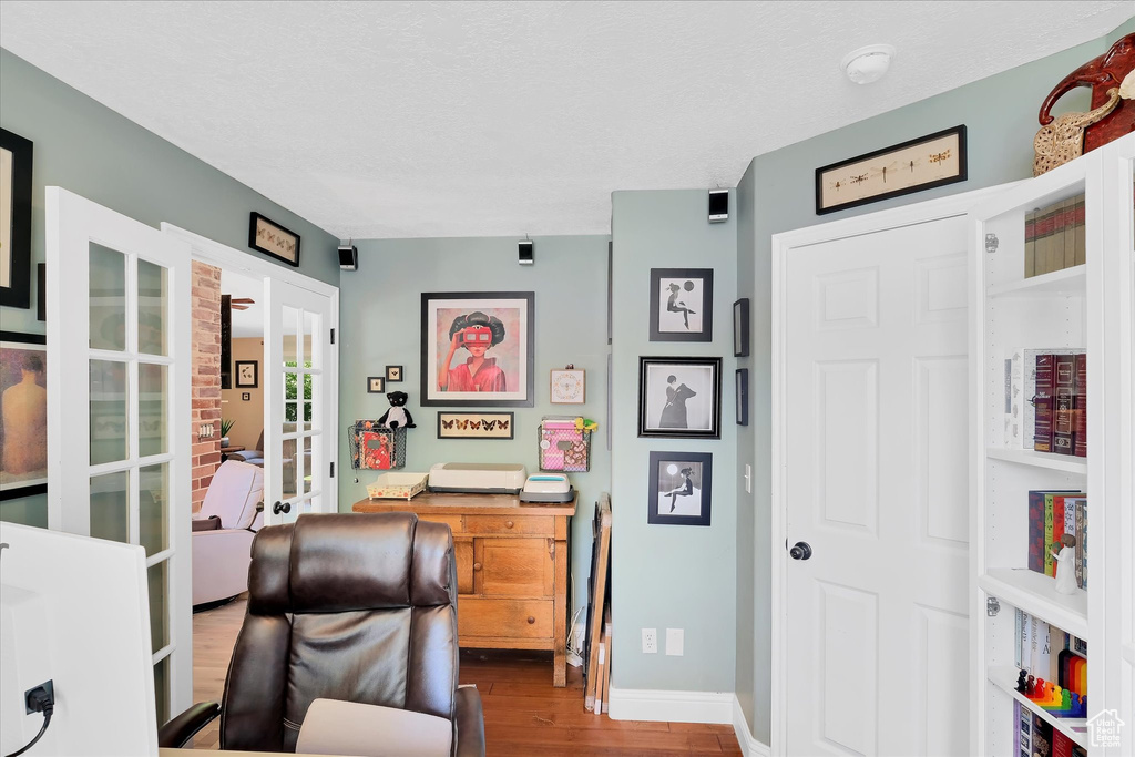 Office space featuring wood finished floors, french doors, baseboards, and a textured ceiling