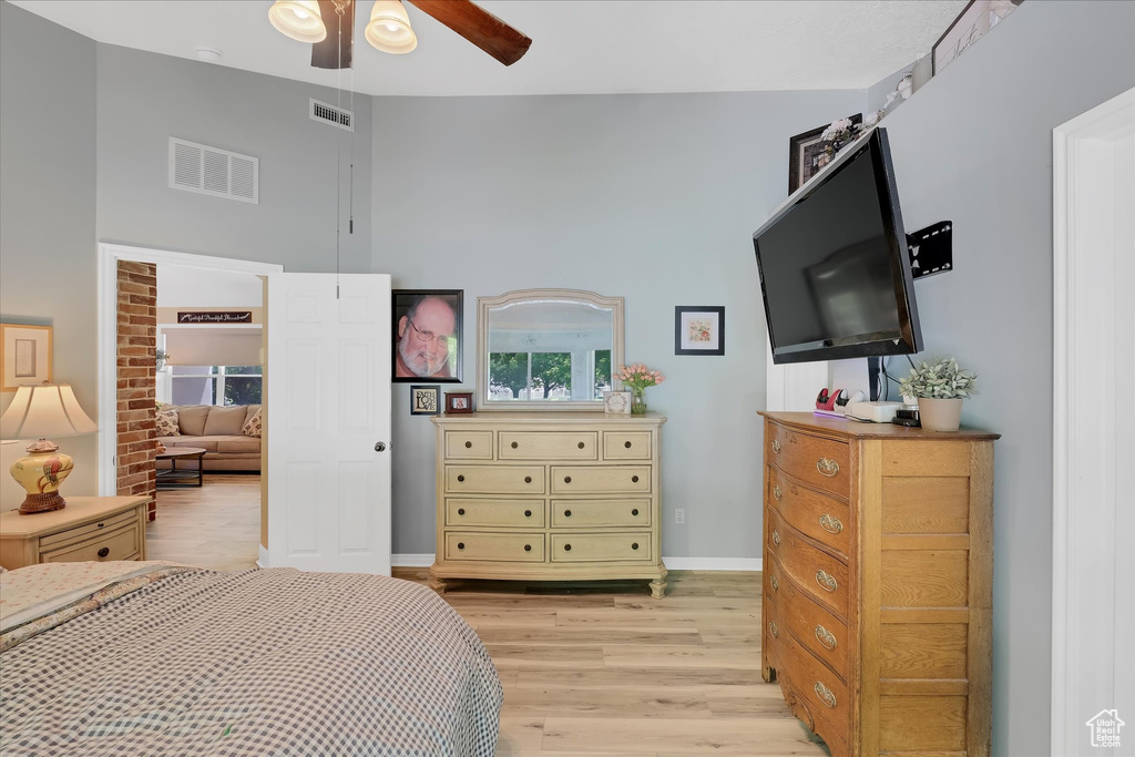 Bedroom with light wood finished floors, a high ceiling, baseboards, and ceiling fan